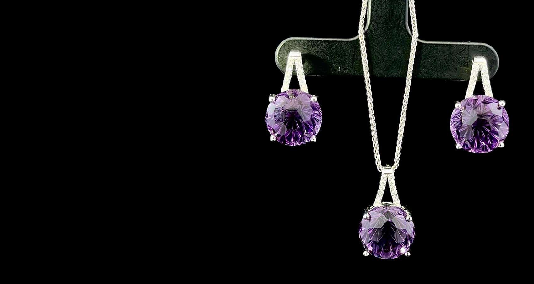 Set of Amethyst Jewelry. Pair of earrings and a pendant on a black background