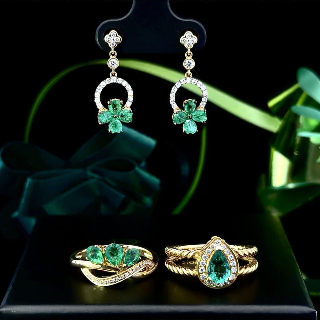 St. Patrick's Day Collection: Shamrock pattern green emerald earrings with accent diamonds above two golden rings with large emeralds and accent diamonds