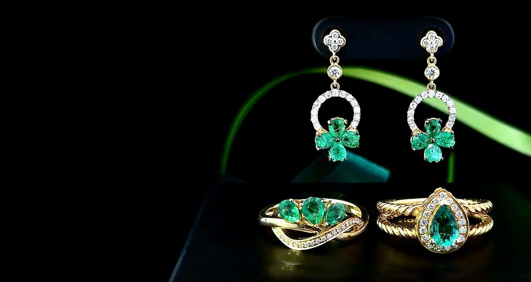 St. Patrick's Day Collection: Shamrock pattern green emerald earrings with accent diamonds above two golden rings with large emeralds and accent diamonds